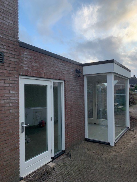 Hoek van de aanbouw met tuindeuren en de nieuwe glazen uitbouw