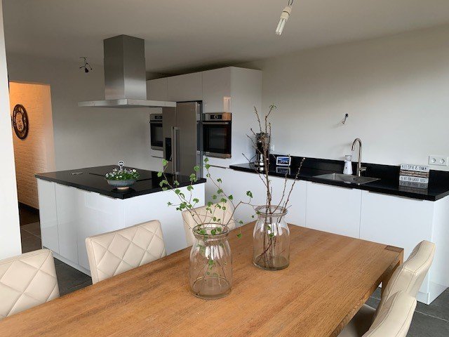 Nieuwe witte keuken met kookeiland en eettafel